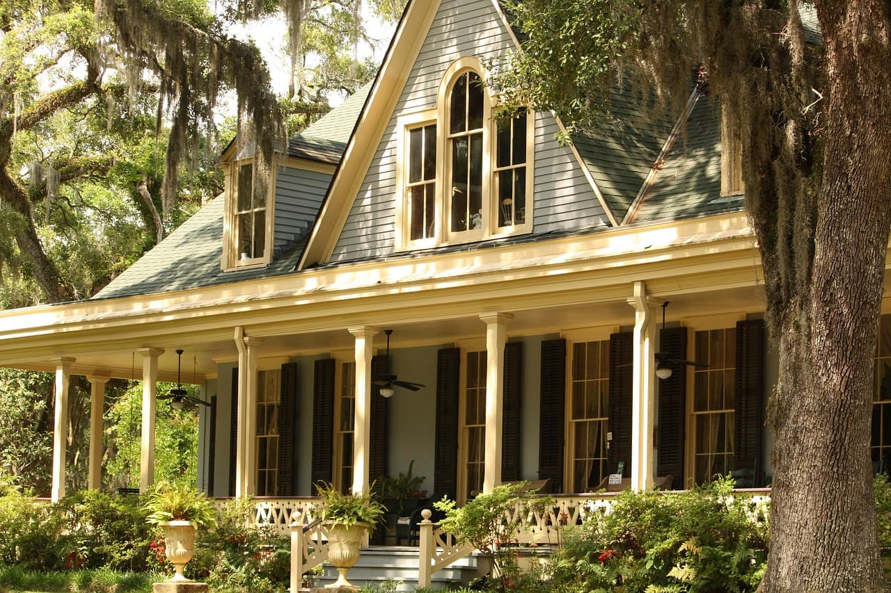 A shaded front porch on a traditional house, the kind of home that feels ready for guests