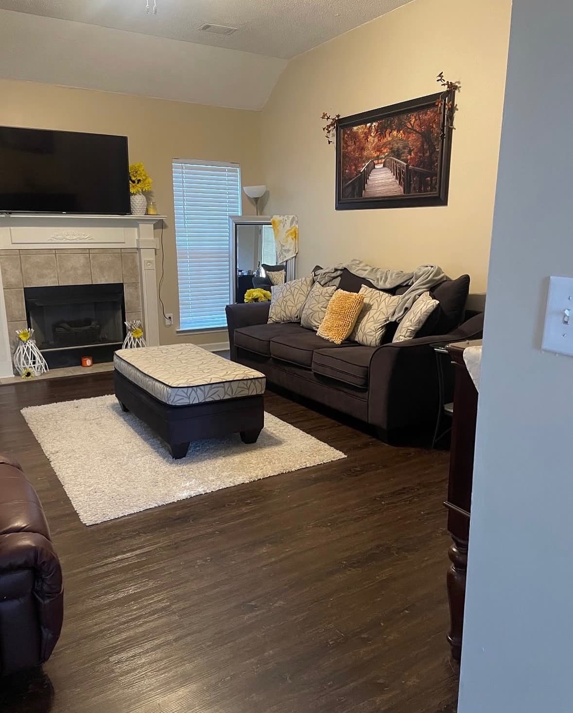 Furnished living room with a fireplace, sofa, and ottoman in a managed home