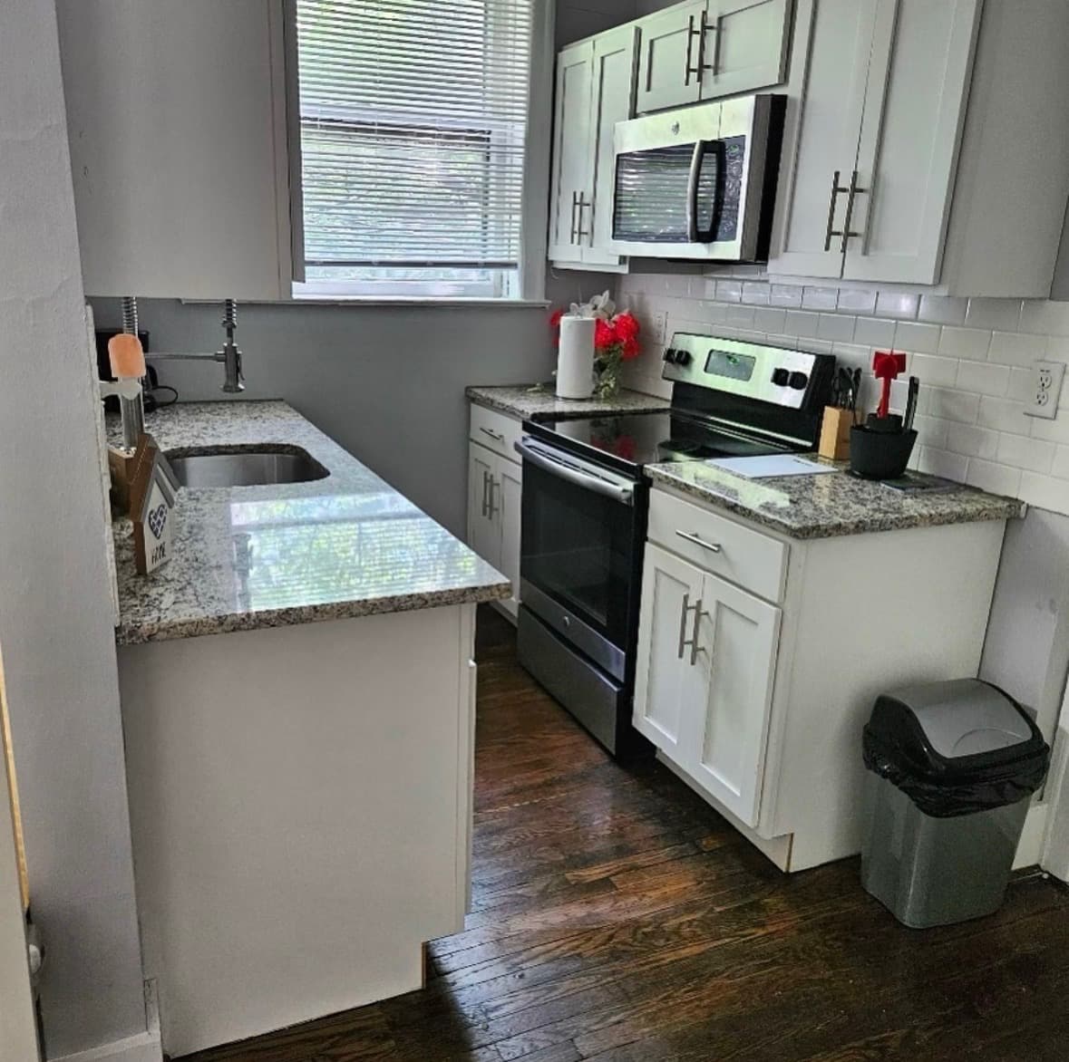 Kitchen in a previous client’s home, with granite counters, white cabinets, and stainless appliances