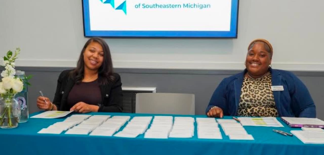 Adults gathering around a community program table during an MB Experiences session
